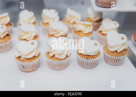 Petits gâteaux délicats recouverts de crème en forme de cœur Banque D'Images