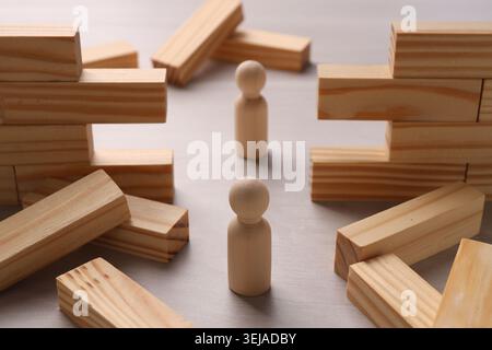 Mur en bois effondré fait de blocs et de figures humaines sur la table, gros plan. Surmonter les obstacles Banque D'Images