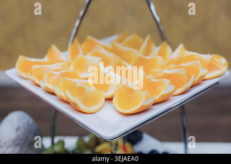 Tranches d'orange fraîches disposées soigneusement sur un plateau blanc Banque D'Images