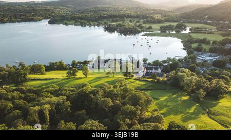 Cette vue aérienne époustouflante capture un village pittoresque au bord du lac baigné par la lueur chaude de la lumière dorée du soleil, mettant en valeur sa charmante arche Banque D'Images