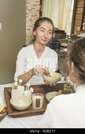 Thérapeute Spa adulte femme caucasien appliquant un masque facial au client dans un cadre de bien-être relaxant Banque D'Images