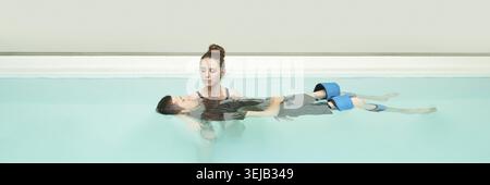 Séance de thérapie aquatique avec thérapeute féminine aidant un jeune patient masculin dans une piscine Banque D'Images