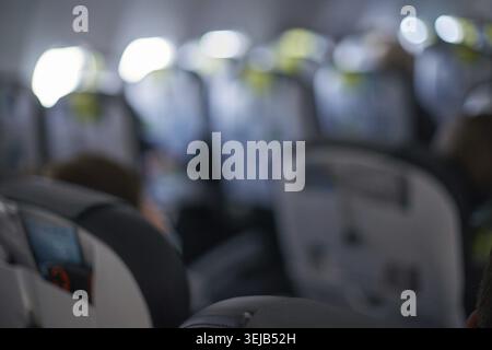 Cabine d'avion floue avec passagers et rangée de sièges en vol Banque D'Images