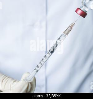 Gros plan du médecin préparant la seringue avec la solution vaccinale transparente pour injection Banque D'Images