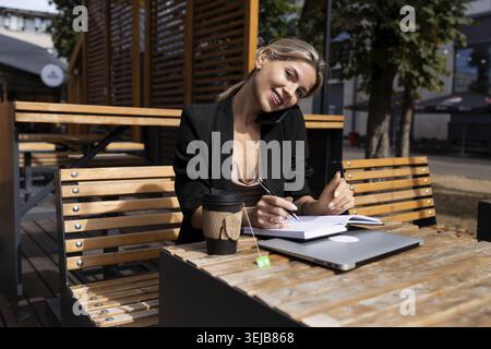Jeune femme d'affaires déjeunant dans un café de la ville avec un journal pour ordinateur portable Banque D'Images