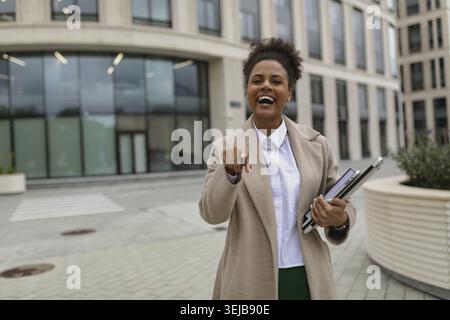 Femme satisfaite homme d'affaires femme afro-américaine avec des émotions joyeuses pointe son doigt vers l'avant avec un large sourire Banque D'Images