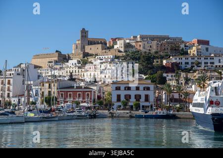 Ibiza, Espagne : vue du port de Marina sur l'eau aux maisons blanches traditionnelles, aux murs de la forteresse historique et à la cathédrale emblématique de Dalt Vila Banque D'Images