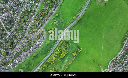 Une perspective aérienne met en valeur le contraste entre les habitations denses et les vastes paysages naturels avec une route qui traverse Banque D'Images