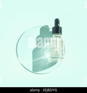 Flacon compte-gouttes transparent pour sérum ou huile avec bouchon noir sur fond bleu pastel avec effet d'ombre Banque D'Images