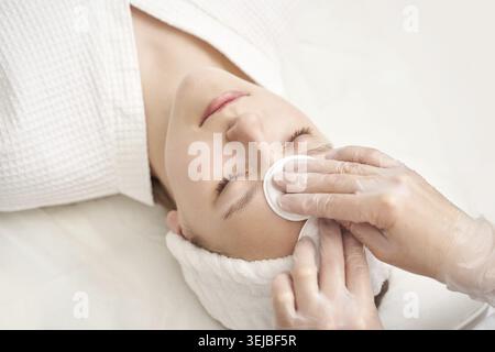 Jeune femme caucasienne recevant un traitement du visage par coton en milieu spa Banque D'Images