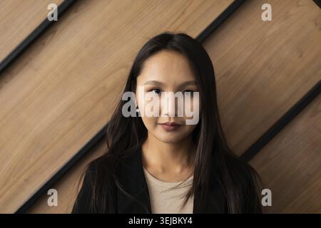 Jeune femme de bureau d'apparence asiatique se tient près du mur Banque D'Images