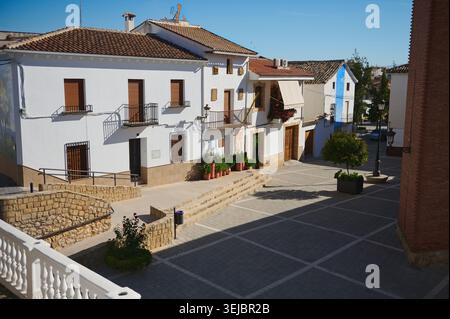 Femme voyageant à travers un petit village espagnol tranquille plaza avec des maisons blanchies à la chaux, des balcons, des plantes en pot et la lumière du soleil chaude, profitant de la médiévale Banque D'Images