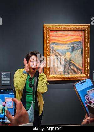 Une touriste asiatique pose imitant la peinture d'Edvard Munch le cri au Musée national d'Oslo, en Norvège, tandis que d'autres prennent des photos sur smartphones Banque D'Images