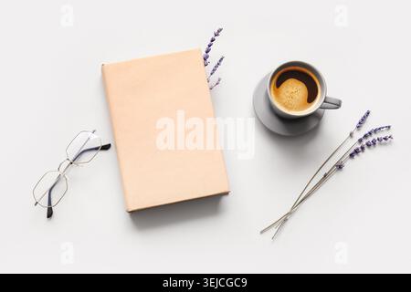 Tasse de café chaud avec livre, lunettes et fleurs de lavande sur fond gris Banque D'Images