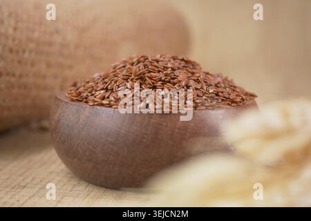 Graines de lin dans un bol en bois sur une table avec du tissu Banque D'Images
