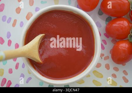 Sauce tomate dans un bol à côté des tomates cerises sur une table Banque D'Images