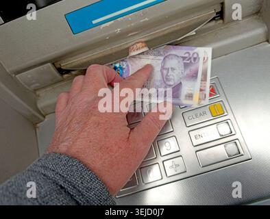 Hand retire un nouveau billet de 20 £ en polymère Charles III d'un distributeur automatique, illustrant l'évolution de l'utilisation de l'argent liquide et de l'accès bancaire en Grande-Bretagne. Banque D'Images