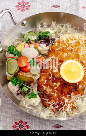 Schnitzel brun doré avec salade de légumes frais dans une poêle Banque D'Images