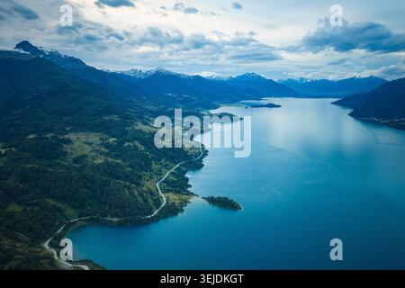 Vue aérienne d'une route sinueuse à côté d'un vaste lac et de montagnes Banque D'Images