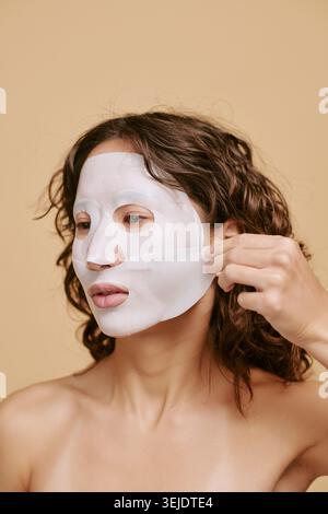 Femme adulte enlevant le masque de feuille pour la routine beauté de soin de la peau Banque D'Images