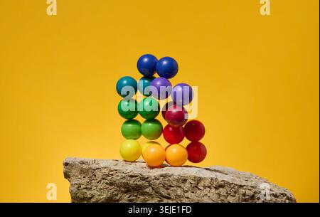Fond abstrait avec des boules en plastique multicolores sur un fond jaune, une scène pour la démonstration de cosmétiques et de prod Banque D'Images