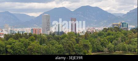 Magnifique panorama aérien sur le paysage urbain de Tirana avec gratte-ciel modernes, arbres verdoyants de Grand Park, et une montagne spectaculaire en toile de fond. Banque D'Images