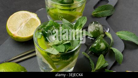 Cocktail mojito rafraîchissant avec citron vert, menthe, fraise et glace sur fond sombre, vue de dessus Banque D'Images