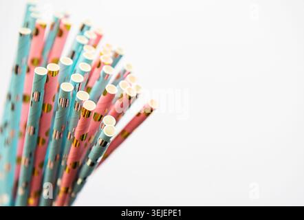 Boire des pailles pointillées pour la fête sur fond blanc avec espace de copie. Vue de dessus de la paille écologique jetable en papier coloré Banque D'Images