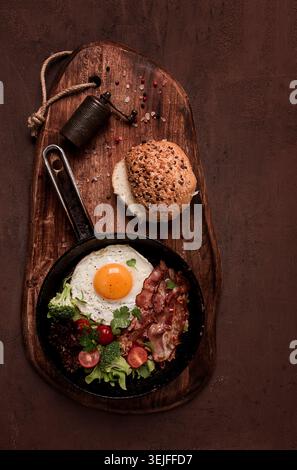 Oeuf frit, avec bacon et légumes, dans une poêle en fonte, vue de dessus, petit déjeuner maison, Banque D'Images