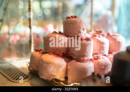 Pyramide de gâteaux roses sur le comptoir. Mini cupcakes mousse de cerise à la fraise sucrée avec des saupoudrages sur le dessus Banque D'Images