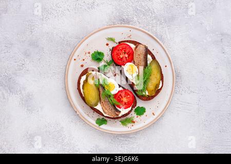 Sandwichs sur pain de seigle, avec sprats, œufs de caille, tomates fraîches et concombre mariné, apéritif, petit déjeuner, fait maison, Banque D'Images