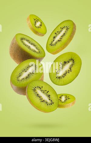 Tranches de kiwi avec une chair verte riche, les graines noires volent comme flux sur fond vert. Parfait pour les aliments antioxydants organiques adver Banque D'Images