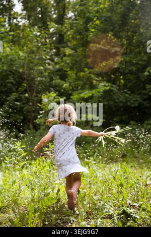 Enfant avec des pissenlits dans la nature. Banque D'Images
