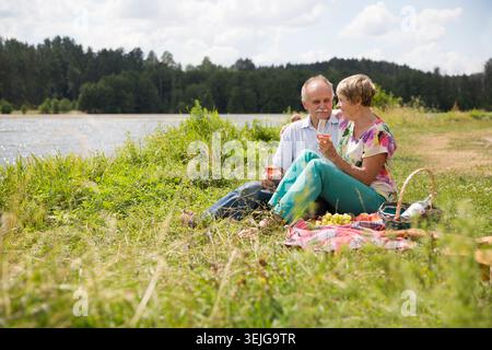 Charmant couple de personnes âgées au lac ayant un pique-nique Banque D'Images