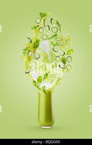 Smoothie de légumes verts frais en verre avec des feuilles vertes volantes, tranches de concombre, légumes, éclaboussures éclatantes sur le dos vert Banque D'Images