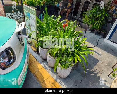 Un véhicule électrique avec un extérieur bicolore blanc et vert branché sur un câble de charge. Phnom Penh, Cambodge, Asie Banque D'Images