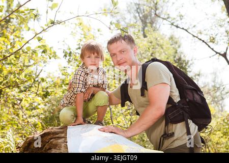Père et fils à la recherche avec la carte relaxant en plein air sur fond vacances d'été et concept de randonnée Lifestyle. Banque D'Images