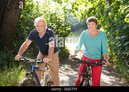 Heureux couple aîné monter à vélo dans le parc Banque D'Images