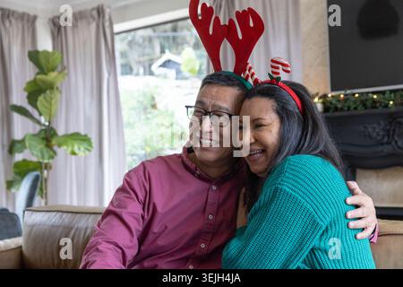 Couple de personnes âgées s'embrassant sur un canapé en cuir dans le salon portant des bandeaux en bois près de la cheminée. Festif, célébration, chaleur Banque D'Images