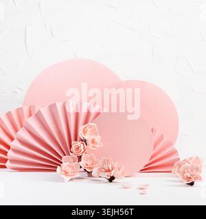 Tendre fond floral de printemps dans le style japonais - fleurs de sakura roses, cercles roses, ventilateurs de papier sur la table blanche comme scène pour pr Banque D'Images
