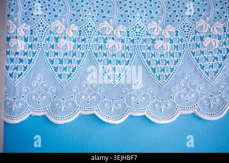 Motif dentelle, détail d'une nappe isolée sur fond bleu. Bordure artistique. Artisanat, vintage. Concept hobby. Vue de dessus. Banque D'Images