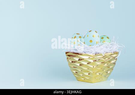Fond de pâques festif - oeufs de pâques bleus avec des pois dorés scintillants dans un bol doré sur fond bleu. Banque D'Images