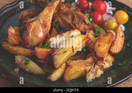 Cuisses de poulet frites avec des tranches de pommes de terre, sur une assiette, cuites au four, avec des épices, maison, pas de gens Banque D'Images