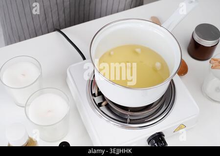 Femme fabriquant des bougies faisant fondre la cire de soja dans le pot Banque D'Images