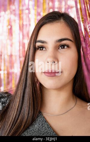 Gros plan de femme en robe à paillettes debout sur fond violet pailleté et or Banque D'Images