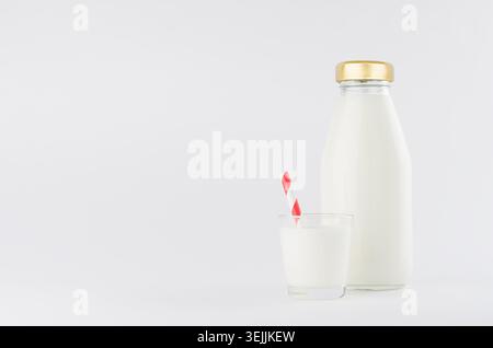 Lait blanc, produit laitier en bouteille de verre maquette avec verre, paille rouge à refus sur fond blanc clair et doux. Banque D'Images