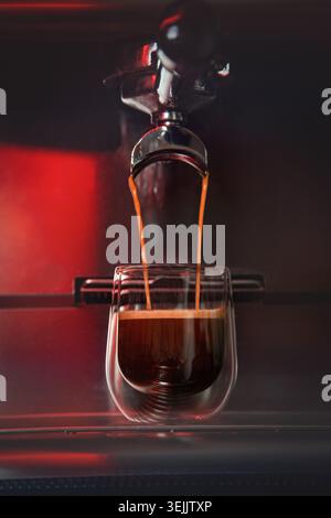 Le café espresso s'écoule d'un porte-filtre dans une tasse en verre à double paroi Banque D'Images