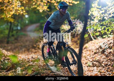 Le VTT navigue sur le sentier forestier d'automne en équipement, en casque et en randonnée dynamique Banque D'Images