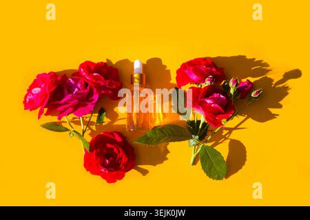 Bouteille en verre cosmétique pour huiles essentielles withrose fleurs sur un fond jaune. Spa Still Life avec sérums naturels en verre bo Banque D'Images