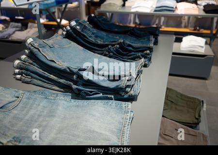 Gros plan d'un pantalon en denim bleu plié soigneusement empilé sur une table d'affichage grise dans une boutique Banque D'Images